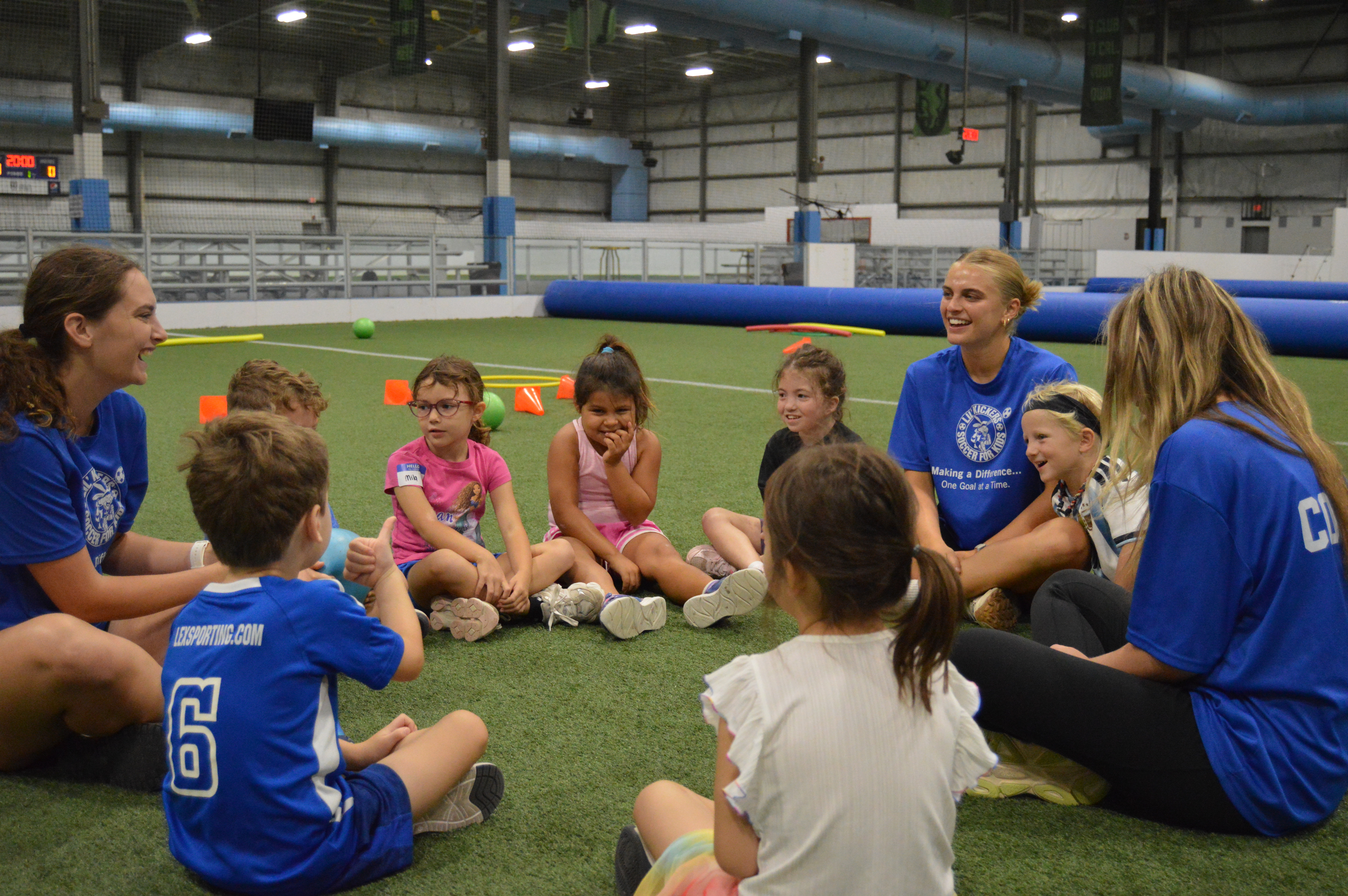 Coaches and kids sitting in a circle indoors